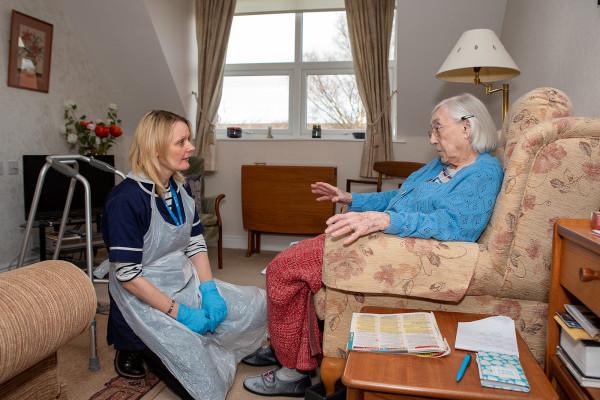 Older woman receiving home care from a professional carer in West Sussex